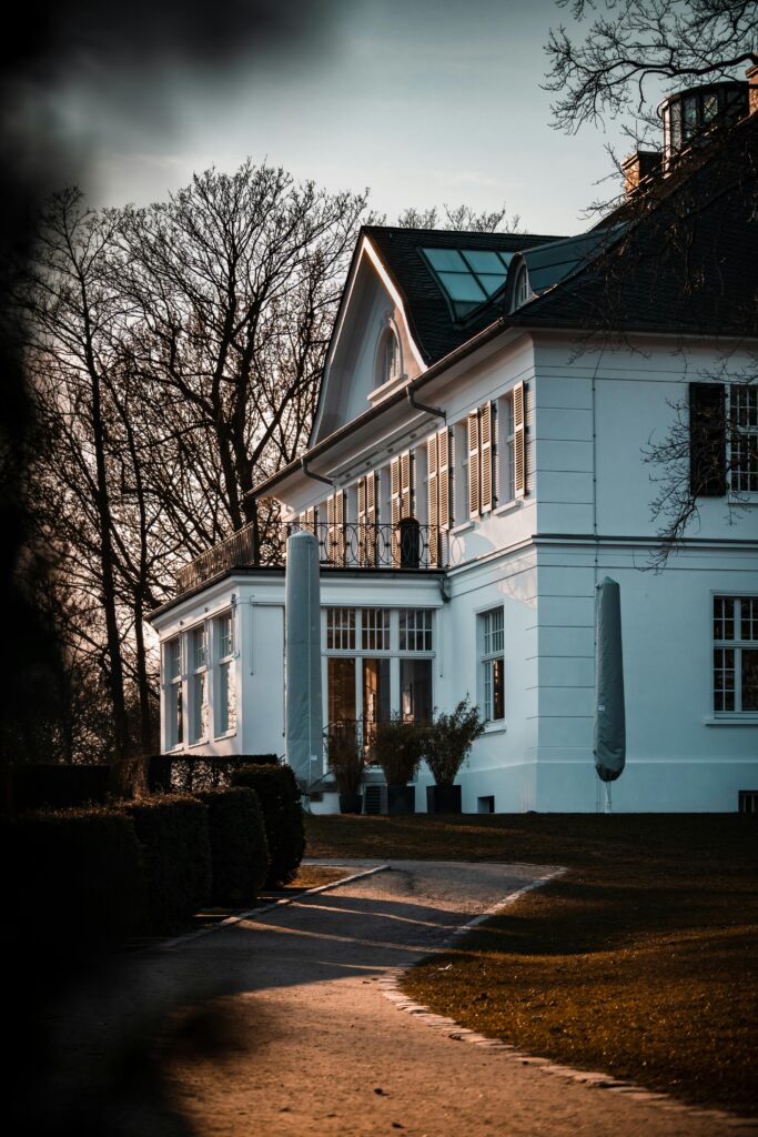 Charming white house with classic architecture and serene garden pathway in Hamburg, Germany at sunset.