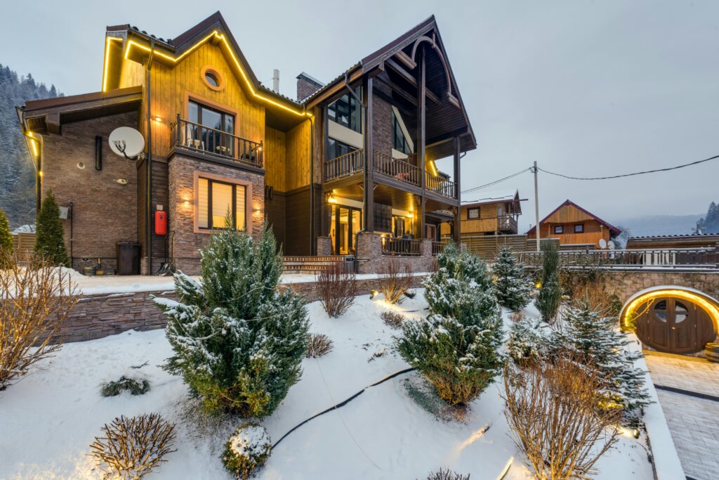 A cozy chalet surrounded by snow and warm lights during winter, perfect for a holiday retreat.
